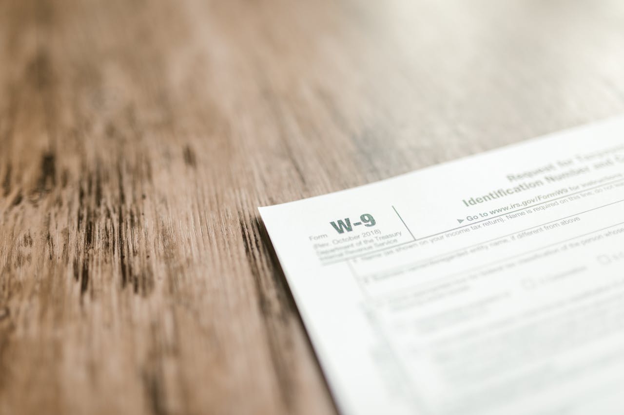 A close-up of a W-9 tax form placed on a wooden desk, emphasizing paperwork and finance.